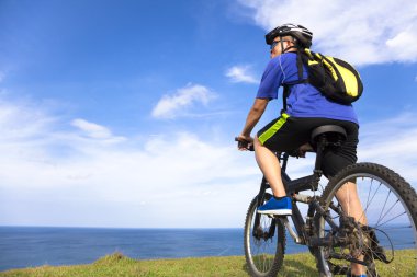 dağ bisikleti üzerinde oturan ve okyanus arayan genç adam