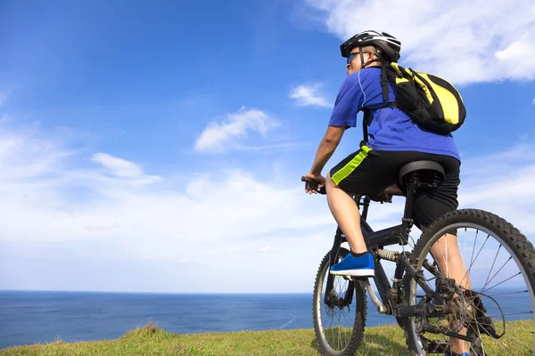 Young man sitting on a  mountain bike and looking the ocean — Stock Photo, Image