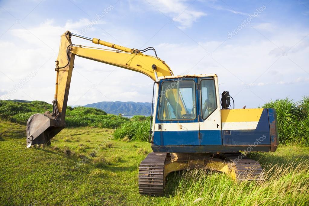 excavator on the meadow with sky and ocean background