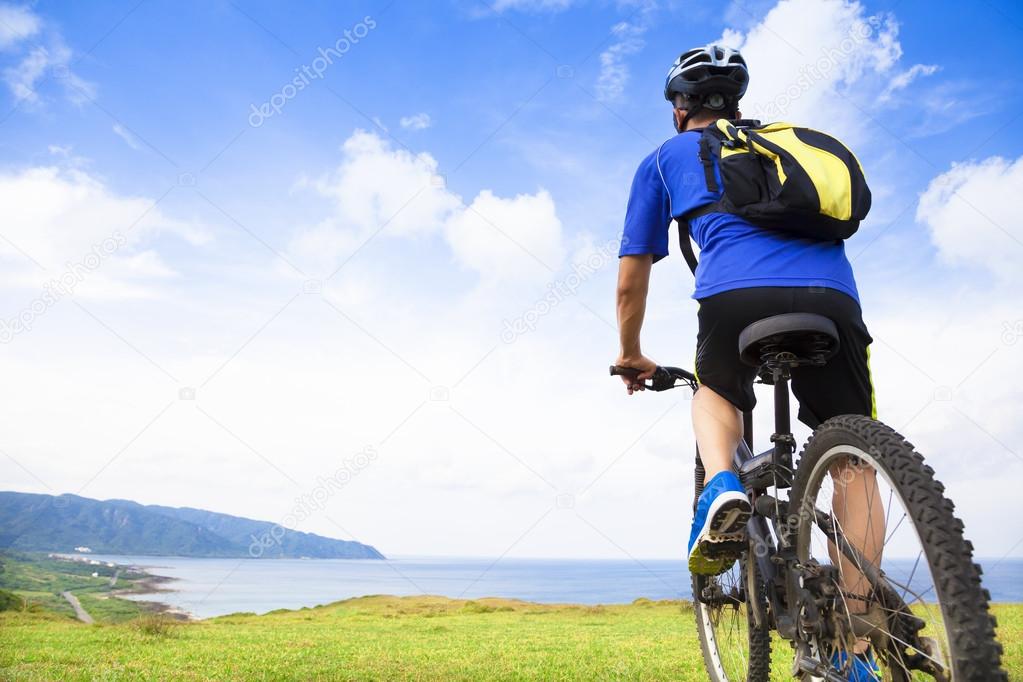 young man sitting on a  mountain bike and looking the ocean