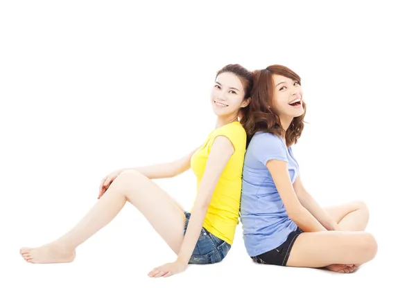 Two smiling  young woman sitting and back to back — Stock Photo, Image