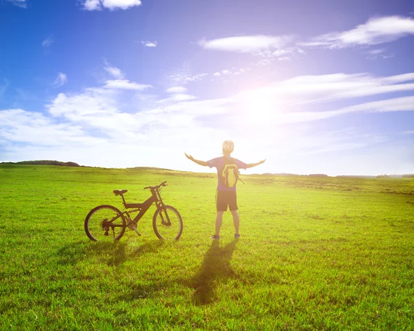 Mochilero de pie junto a la bicicleta con el fondo del amanecer — Foto de Stock