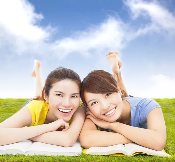 Happy pretty students lying on the grassland with books — Stock Photo, Image