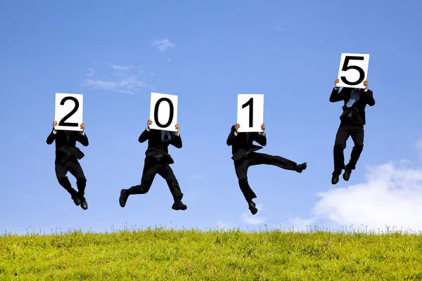 Empresario celebración 2015 y saltar en un prado — Foto de Stock