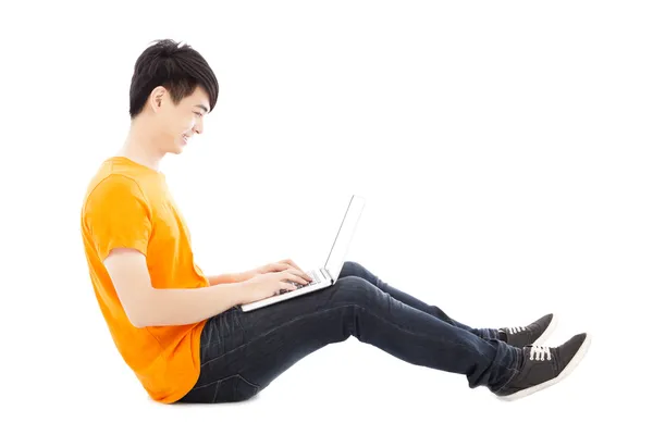 Joyeux jeune étudiant assis sur le sol et utilisant un ordinateur portable — Photo