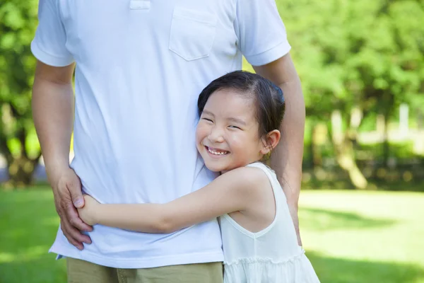 Sorridente bambina abbraccio padre in vita nel parco — Foto Stock