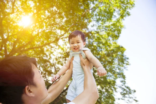 Pai levantando seu pequeno filho sorridente no alto — Fotografia de Stock