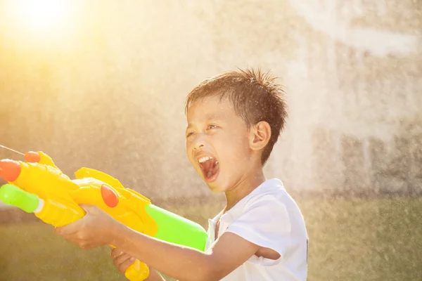 幸せな小さな男の子叫んでいると公園で水銃を再生 — ストック写真