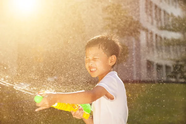 Vrolijk jongetje spelen water kanonnen in het park — Stockfoto