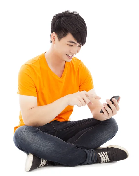 Lachende jonge student zittend op de vloer en ontroerend smartphone — Stockfoto
