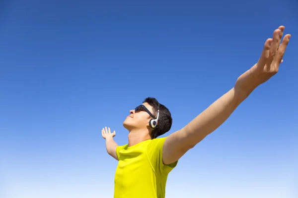 Joven disfrutando de la música con fondo de cielo azul — Foto de Stock