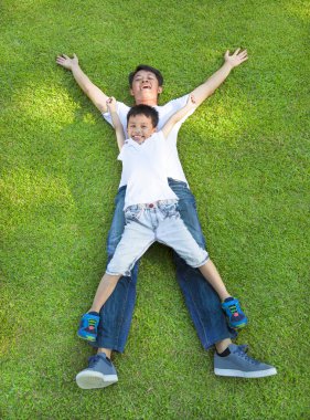 mutlu baba ve oğul birlikte bir çayır üzerinde yalan