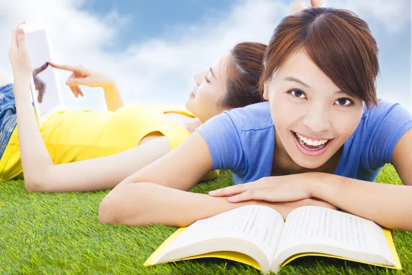 Sonriendo bonitos estudiantes acostados en el pastizal con libros — Foto de Stock