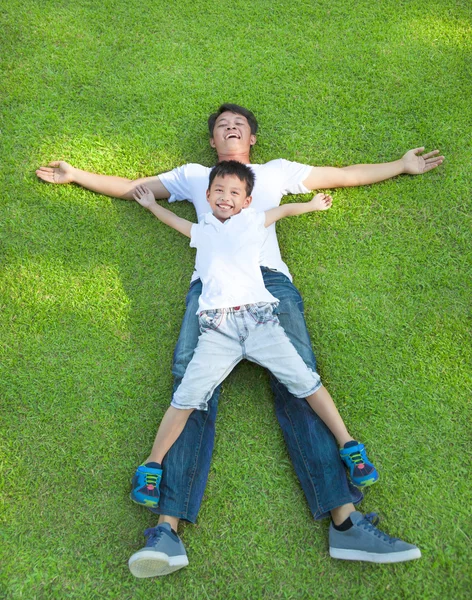 Vater und Sohn liegen gemeinsam auf einer Wiese — Stockfoto