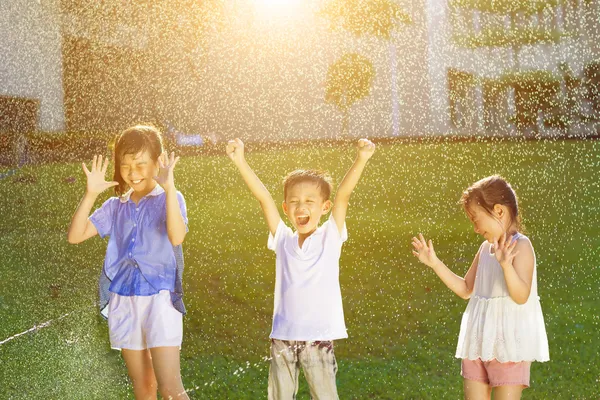 Bambini felici si divertono a giocare nelle fontane d'acqua — Foto Stock