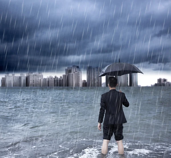 Uomo d'affari in possesso di un ombrello e in piedi con cloudburst — Foto Stock