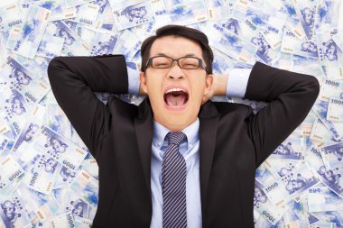 Yeni Tayvan Doları yığınlarının üzerinde yalan mutlu iş adamı