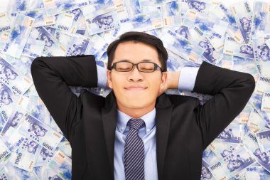 business man enjoying and lying on the stacks of money clipart