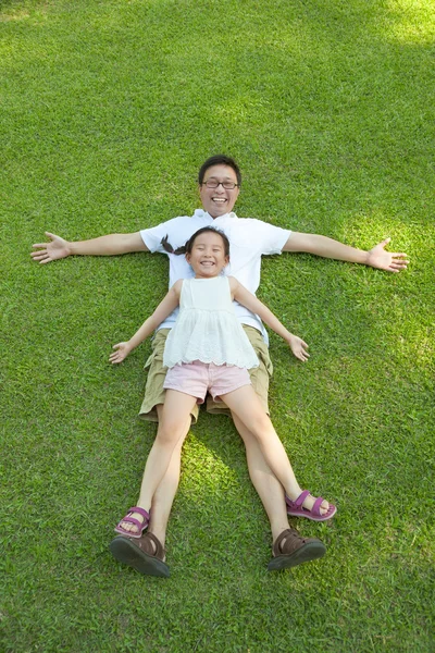 Padre e hija tendidos en un prado juntos —  Fotos de Stock