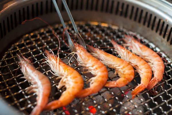 Chef grilling shrimps on flame with tongs — Stock Photo, Image