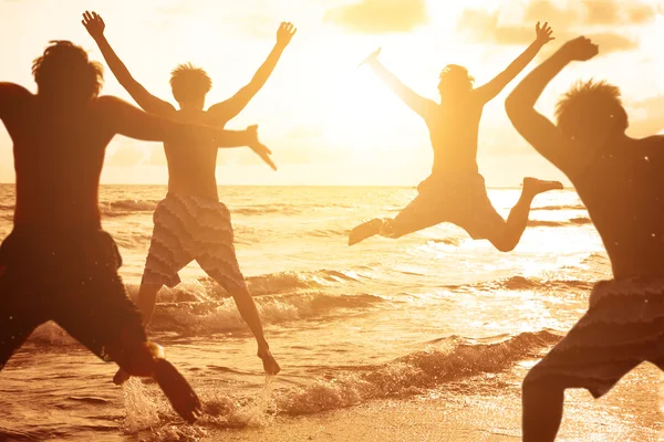 Grupo de jovens pulando na praia — Fotografia de Stock