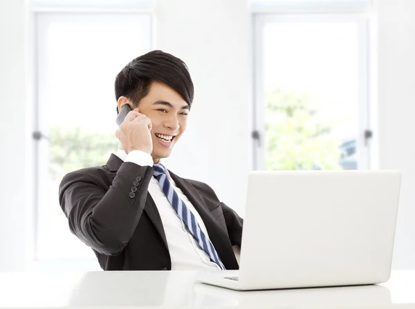 Молодий бізнесмен щасливо розмовляє смартфоном в офісі — стокове фото
