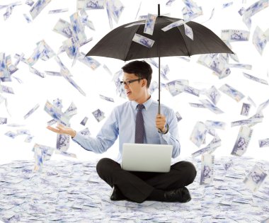 business man holding a umbrella and catching money clipart