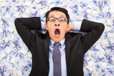 excited  business man lying on the new taiwan dollar clipart