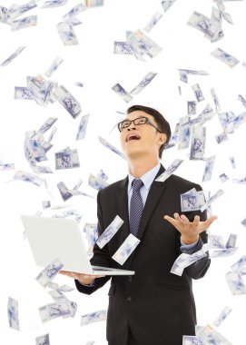 happy business man holding a laptop and  catching money clipart