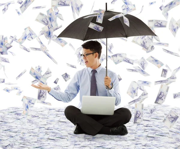 Homem de negócios segurando um guarda-chuva e pegar dinheiro — Fotografia de Stock