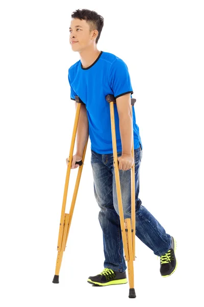 Young asian man on crutches. white background — Stock Photo, Image