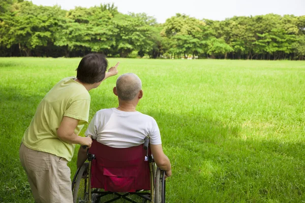 Uomo anziano seduto su una sedia a rotelle con sua moglie — Foto Stock