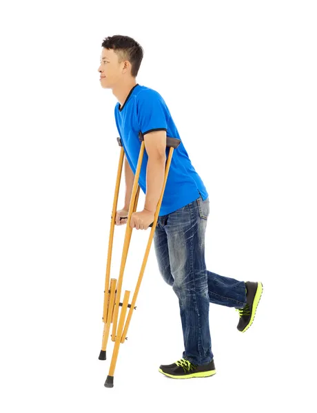 Full length of  young asian man on crutches. white background — Stock Photo, Image