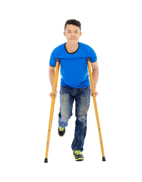 Smiling Young asian man on crutches. white background — Stock Photo, Image