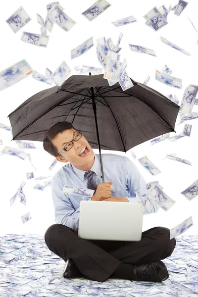 Glücklicher Geschäftsmann, der auf dem Boden sitzt und einen Regenschirm hält — Stockfoto