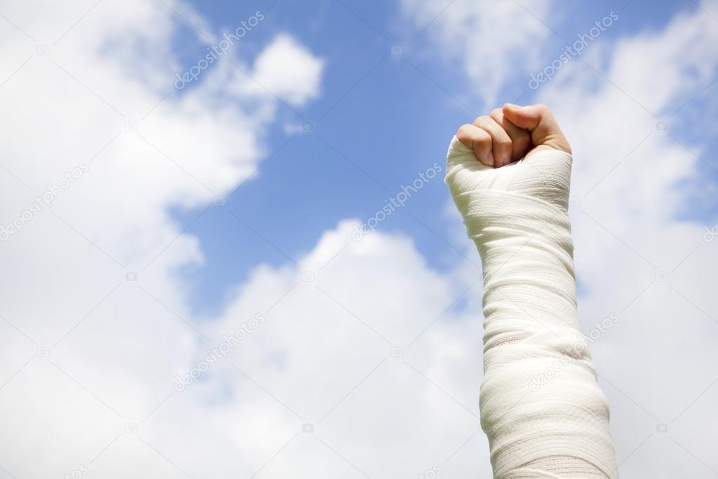 raise bandaged arm  with blue sky background