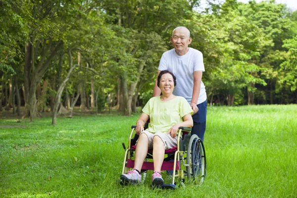 Asiatiska senior kvinna sitter på en rullstol med sin make — Stockfoto