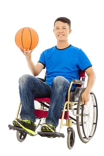 Hopeful young man sitting on a wheelchair with a basketball — Stock Photo, Image