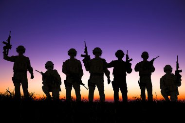 Soldiers silhouettes against a sunset or sunrise background 