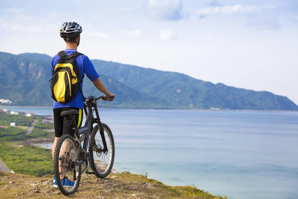 Jonge man die op de berg met fiets — Stockfoto