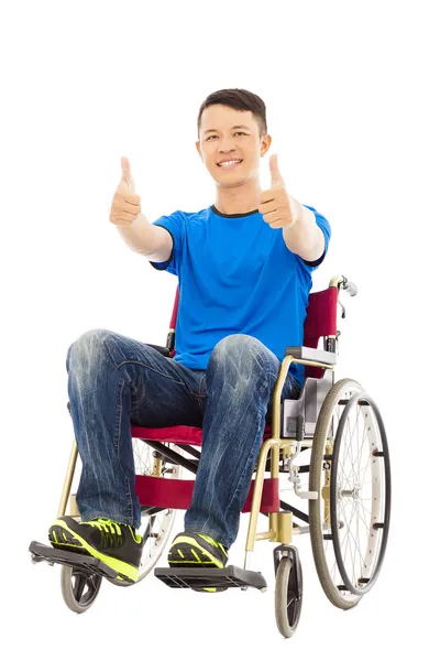 Glücklicher junger Mann sitzt im Rollstuhl und Daumen hoch — Stockfoto