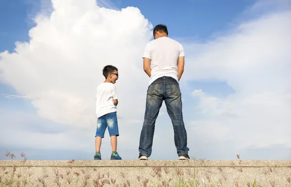Pai e filho de pé em uma plataforma de pedra e mijar juntos — Fotografia de Stock