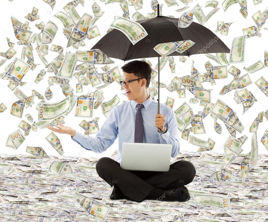 Young business man holding a umbrella with dollar rain
