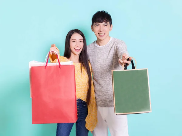 ショッピングバッグを示す幸せなカップル 青の背景に隔離 — ストック写真