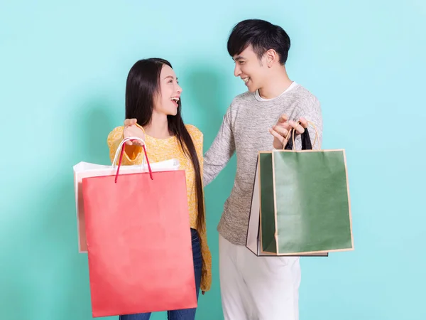 ショッピングバッグで幸せなカップル お互いを見て 青の背景に孤立 — ストック写真