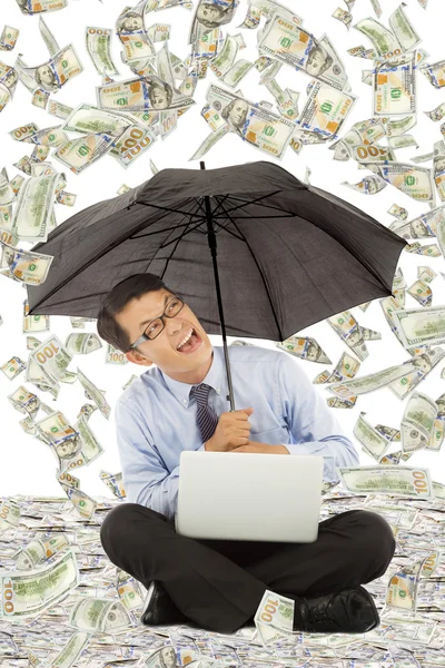 Homem de negócios feliz sentado no chão com a chuva dólar — Fotografia de Stock