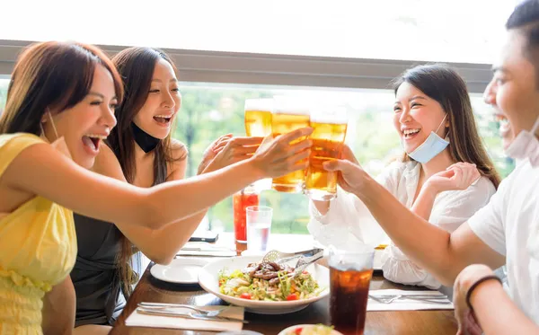Happy Friends Πίνοντας Μπύρα Στο Εστιατόριο Μάσκα Προσώπου Για Προστατεύεται — Φωτογραφία Αρχείου