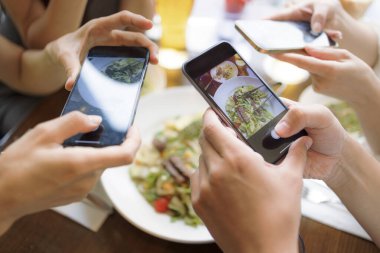 İnsanlar yemekten önce akıllı telefonlarıyla fotoğraf çekiyorlar. en üstteki görünüm.