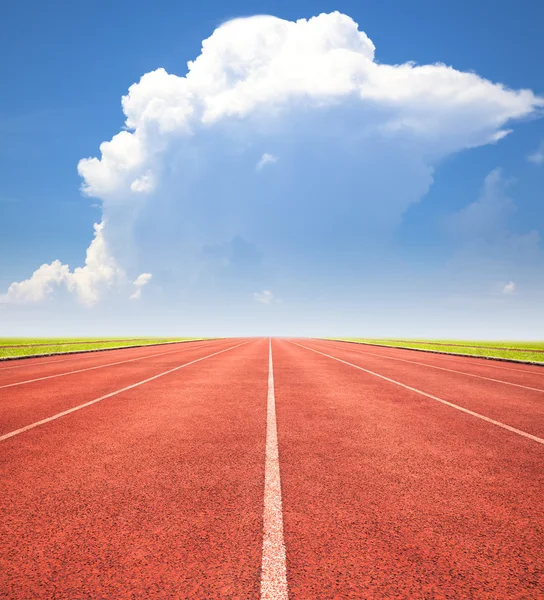 Red running track over blue sky and clouds — Stock Photo, Image