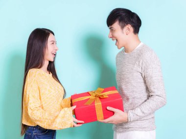 Mutlu genç çift, Çin 'in yeni yılını kutluyor ve mavi arka planda bir hediye kutusu tutuyor..